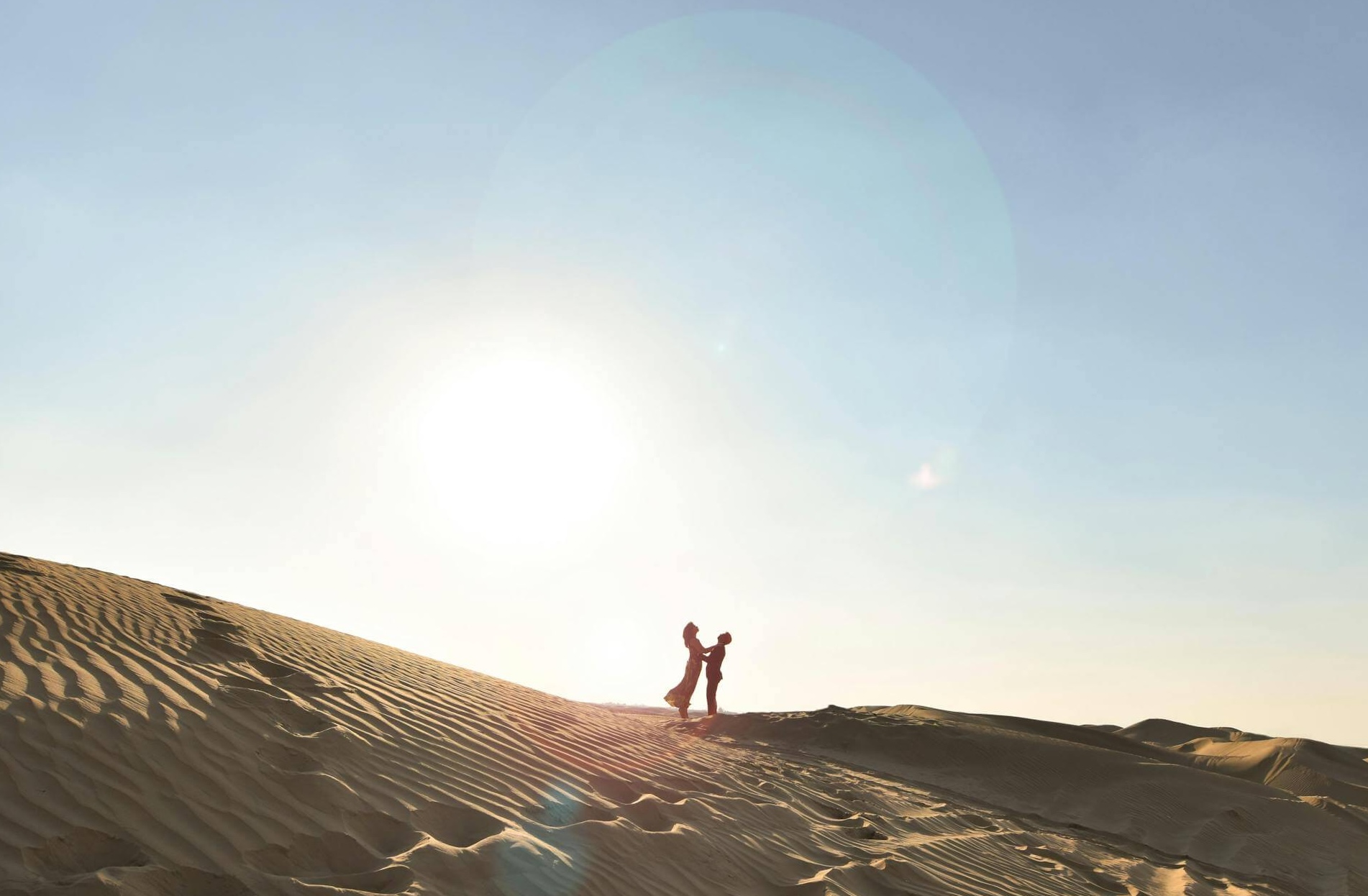 a couple in sand dunes at sunset