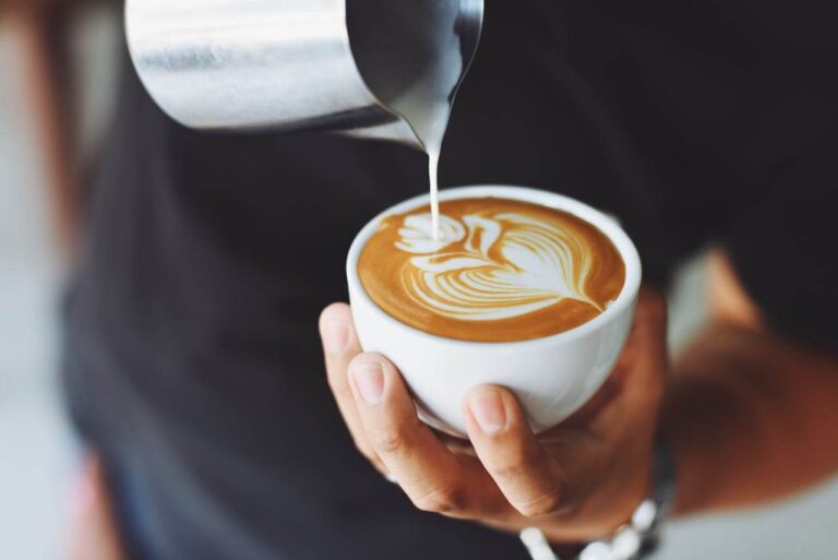 person pouring milk into coffee making latte art